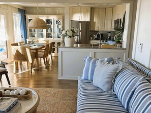 A modern kitchen with a central island, dining area with wicker chairs, and a striped sofa. - Oceanfront Sanctuary in Hilton Head Island (Hilton Head Island)