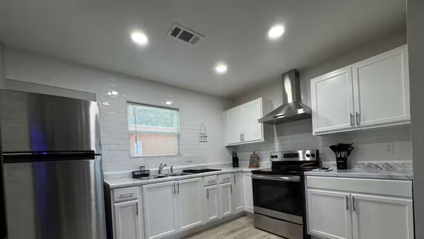 A modern kitchen with white cabinets, stainless steel appliances, and a wooden floor. - 1 BEDROOM with code lock. SHARED SPACE . 30 day minimum stay.  (Arlington)