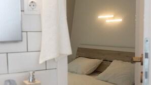 Ett sovrum med en säng, ett sängbord, ett litet bord och en väggmonterad lampa.