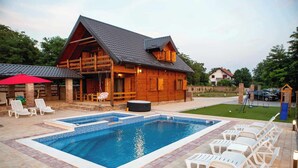 A wooden cabin with a swimming pool, lounge chairs, and a hot tub. - House by the Danube with jacuzzi, pool and kids’ playground (Vukovar)