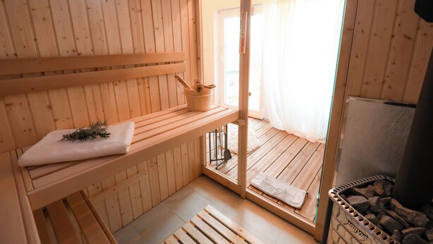 Puisesta laudelankkuineen, kiukaineen ja verhoilla varustetusta ikkunasta koostuva saunatila.