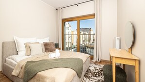 Camera d'albergo con un letto, un comodino, uno specchio e vista sugli edifici attraverso un'ampia finestra.