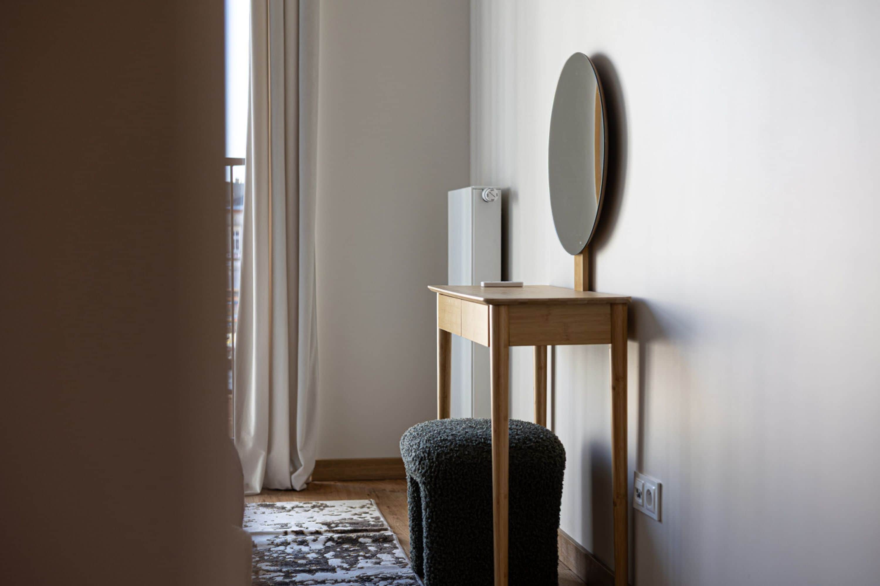 A minimalist room with a wooden table, a mirror, and a small white appliance.