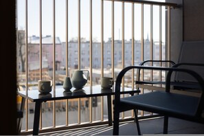 A balcony with a table, chairs, and a view of buildings across a body of water. - Venecia Apartament Balkon Nowy Port Bydgoszcz (Bydgoszcz)