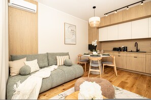 Un espace de vie compact comprenant un canapé, une table à manger et un coin cuisine.