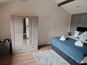 Une chambre à coucher comprenant un lit, une armoire, une table de chevet et un miroir.