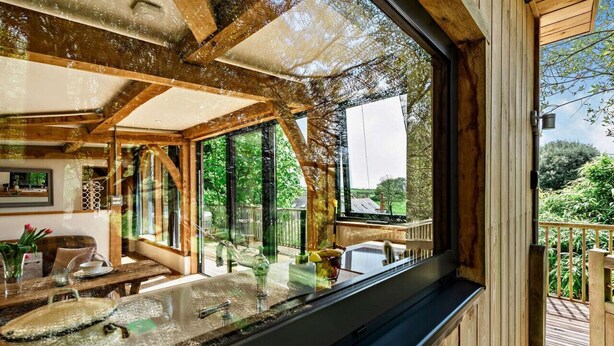 Interno in legno con un'ampia finestra che si affaccia su un patio e vegetazione.