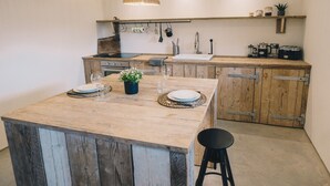 Una cucina con isola centrale, mobili in legno, utensili pensili e lampade a sospensione.