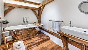 Een badkamer met een houten wastafelmeubel, een bad en een grote spiegel.