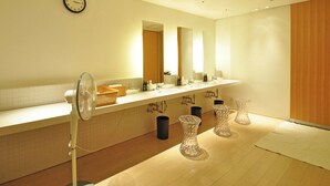 Un bagno moderno con un ampio lavabo, una sveglia a parete e uno specchio grande.