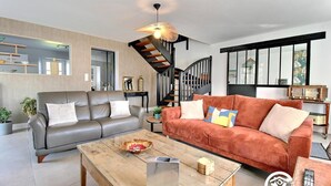 Ein modernes Wohnzimmer mit einem grauen Sofa, einem roten Sofa, einem Holztisch und einer Treppe mit schwarzer Geländer.