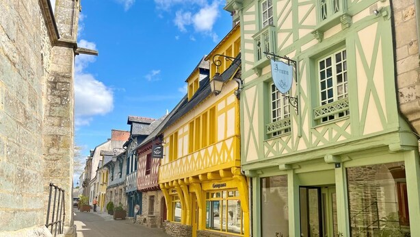 Eine enge Straße, gesäumt von farbenfrohen Fachwerkhäusern, darunter ein grünes Gebäude mit dem Schild 'Arwen'.