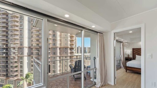 Una habitación de hotel moderna con balcón, ventanas amplias y vistas a rascacielos.