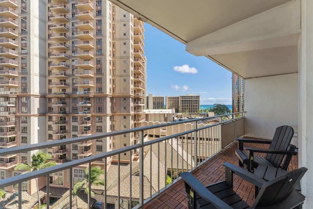 Un balcon donnant sur des immeubles de grande hauteur, avec une balustrade et deux chaises.