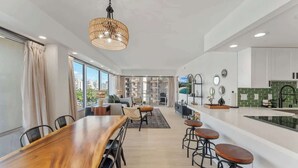 Una cocina moderna con una isla central, taburetes de bar y un comedor con una mesa de madera grande.
