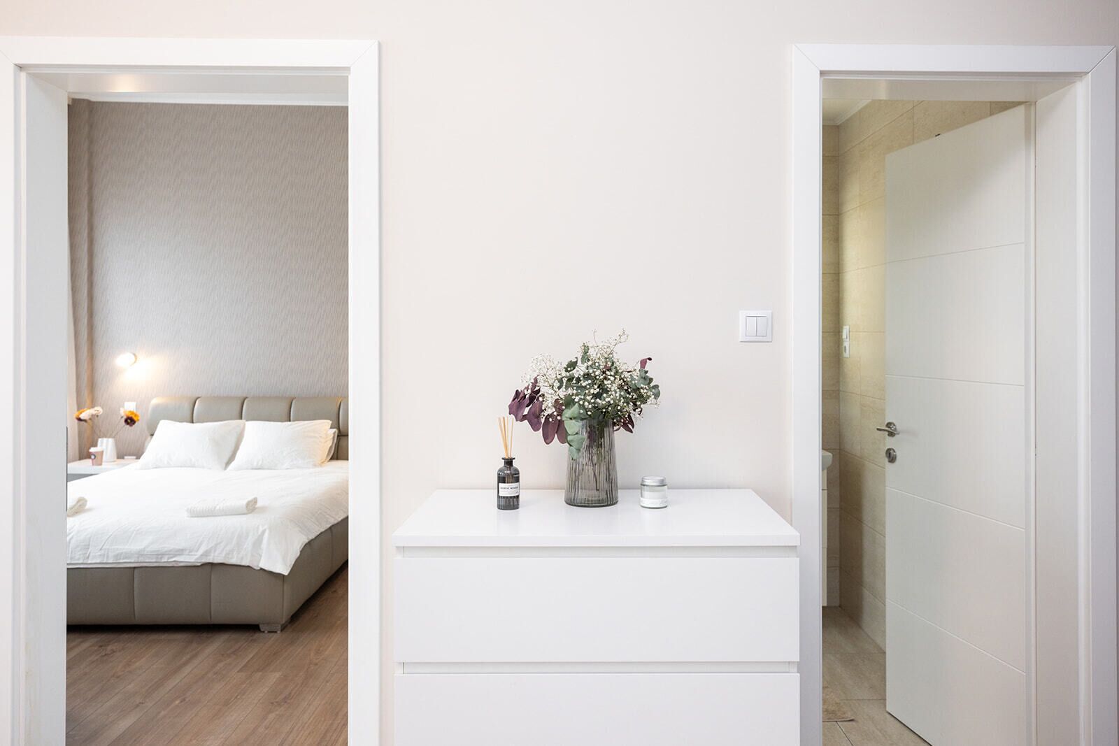 A hotel room with a bed, bedside table, and a door leading to a bathroom.