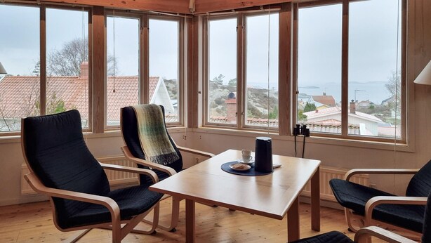 A cozy room with a wooden table, two chairs, and a view of a town through large windows. - Awesome home in Fiskebäckskil with house sea view (Fiskebäckskil)