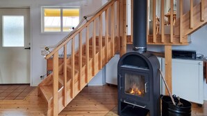 A wooden staircase leading to a room with a wood-burning stove. - Awesome home in Fiskebäckskil with house sea view (Fiskebäckskil)