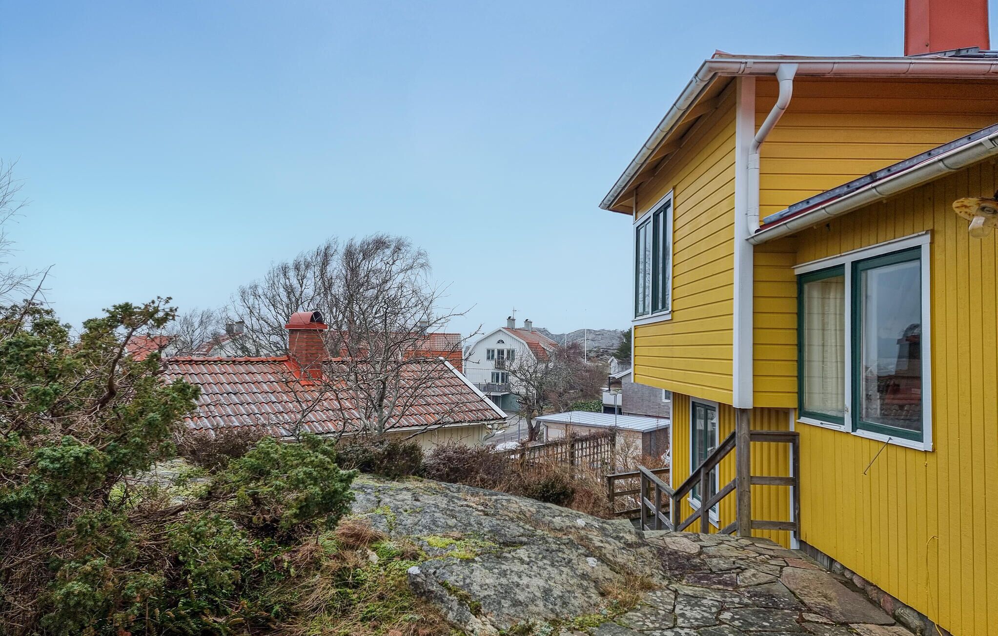 Un bâtiment jaune avec un escalier en pierre menant à une terrasse en bois.