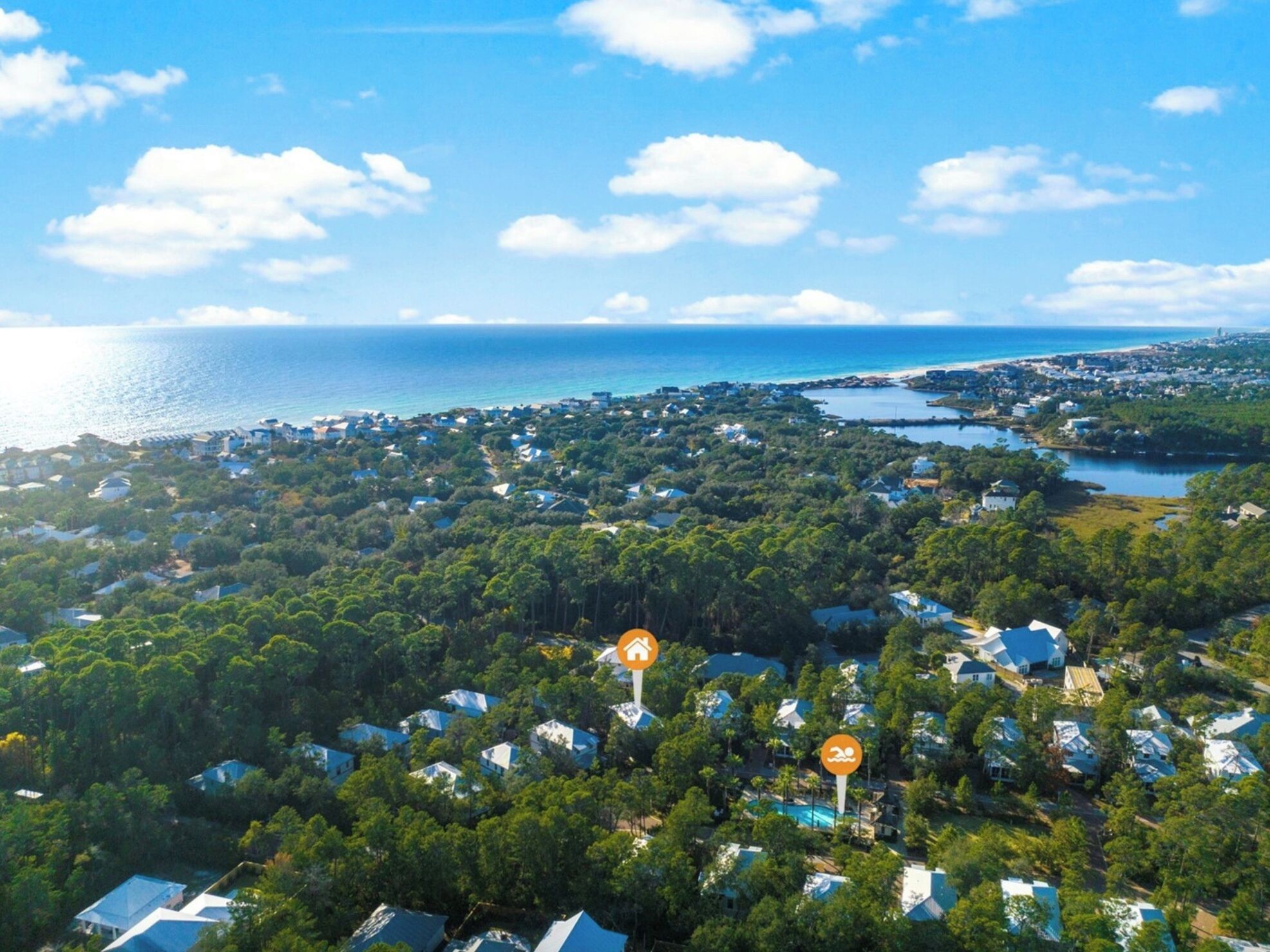 An aerial view of a coastal residential area with houses surrounded by dense greenery.