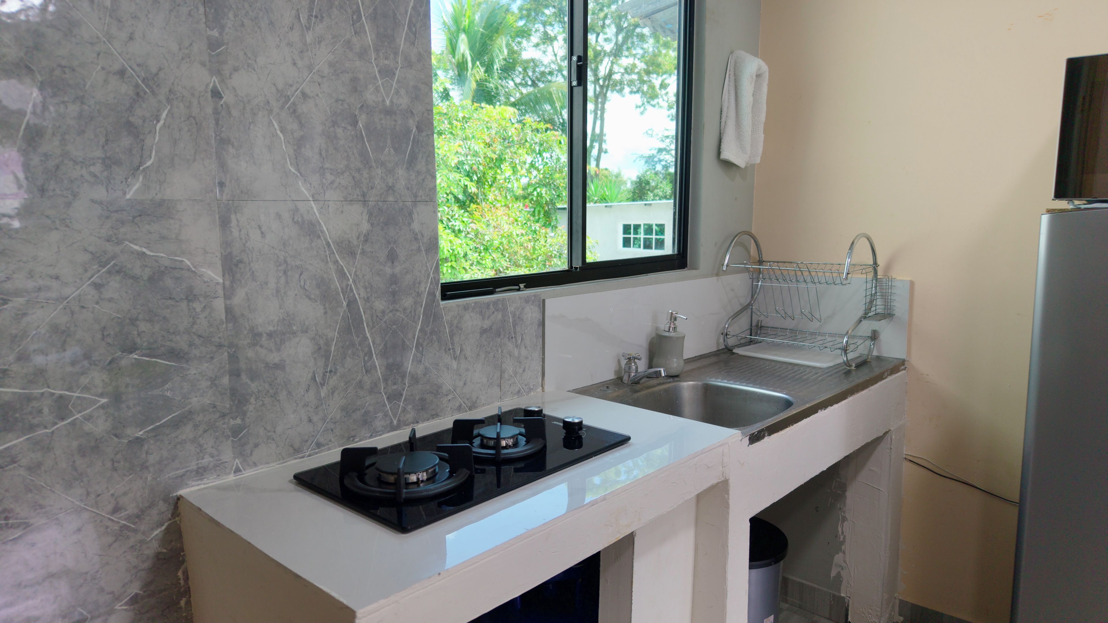 A kitchen with a gas stove, two sinks, a window, and a towel hanging on the wall.