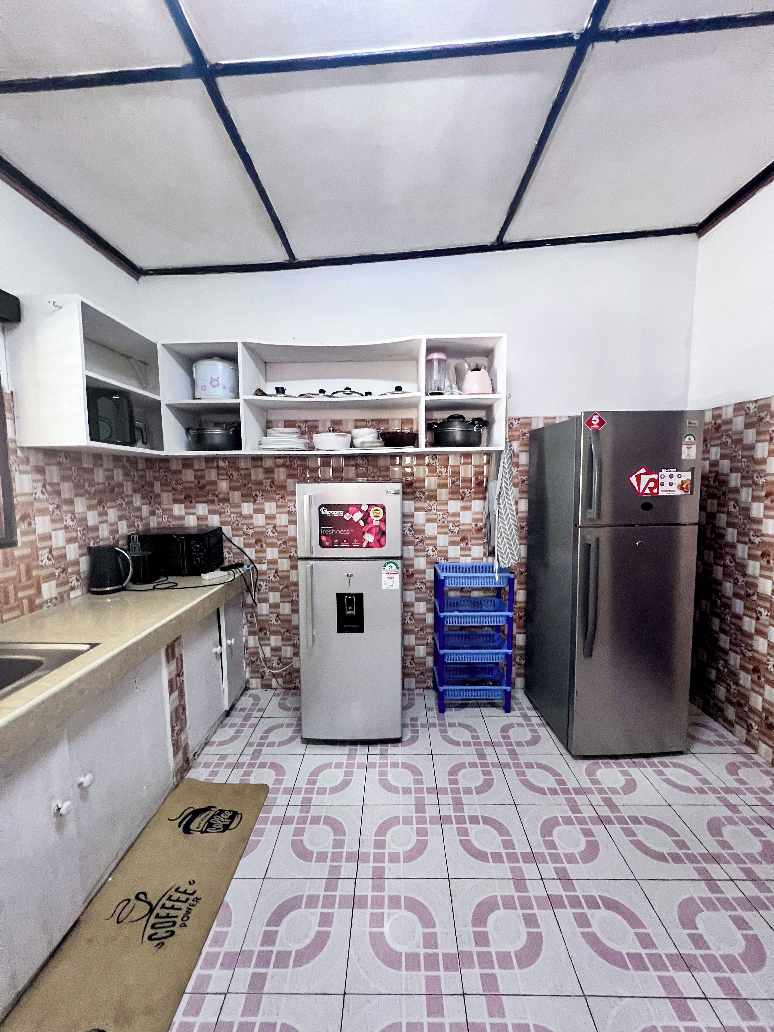 Eine kompakte Küche mit weißen Schränken, einer Mikrowelle, einem Kühlschrank und einer Kaffeemaschine.