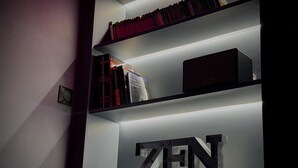 Une bibliothèque remplie de livres, avec une pancarte portant l'inscription « ZEN » sur l'étagère du bas.
