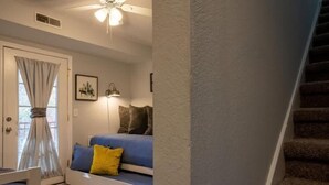 A cozy room with a blue sofa, a small table, a lamp, and a staircase. - FIREFLY LODGE E (Gatlinburg)