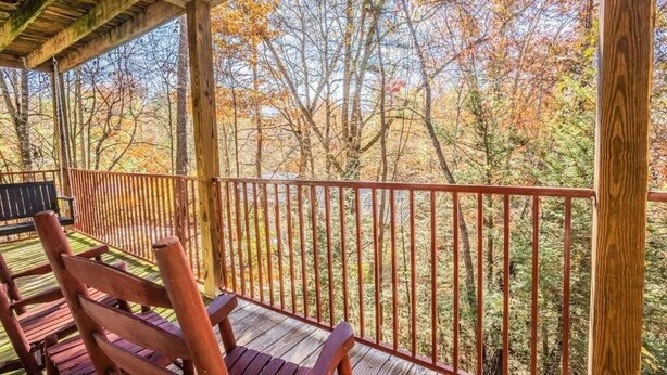 A wooden deck with a railing, wooden chairs, and a bench. - FIREFLY LODGE E (Gatlinburg)