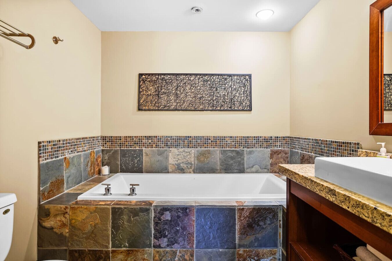 A bathroom with a freestanding bathtub, a sink with a marble countertop, and a mosaic tile backsplash.