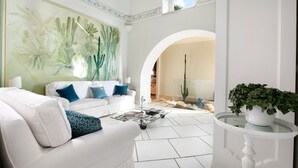Una sala de estar moderna con un sofá blanco, una mesa de centro y un cactus en una vitrina de vidrio.