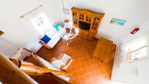 Una habitación con un armario de madera, televisión, candelabro y ventana.