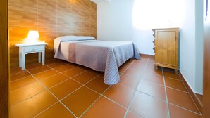 Un dormitorio con cama, mesita de noche, lámpara y armario de madera.