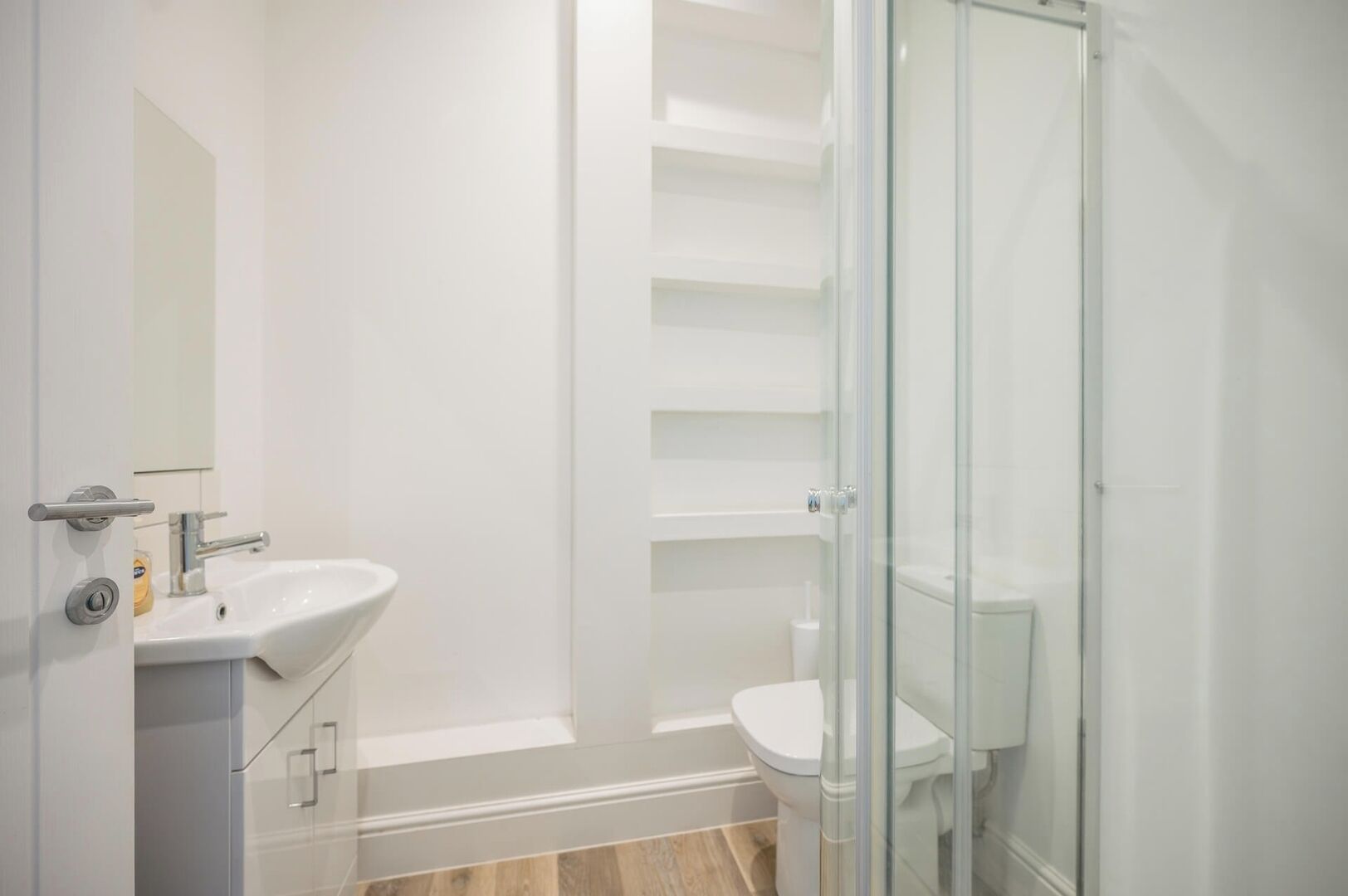A modern bathroom with a glass shower enclosure, a white sink, and a toilet.