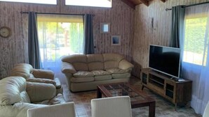 Una sala de estar con sofá, televisor y techo de madera.