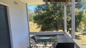A covered outdoor patio with a grill, a table with chairs, and a welcome mat. - Country cottage in the heart of the Yarra Valley (Seville)