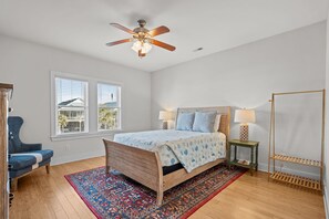 Ein Schlafzimmer mit einem hölzernen Bett, zwei Nachttischlampen, einem Deckenventilator und einem Fenster mit Jalousien.