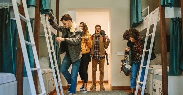 Un dormitorio con literas, una escalera y una puerta que da a otra habitación.