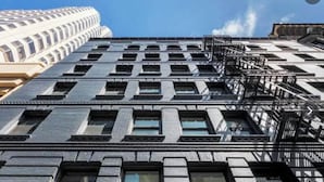 A multi-story building with a classic architectural style, featuring large windows and fire escapes.