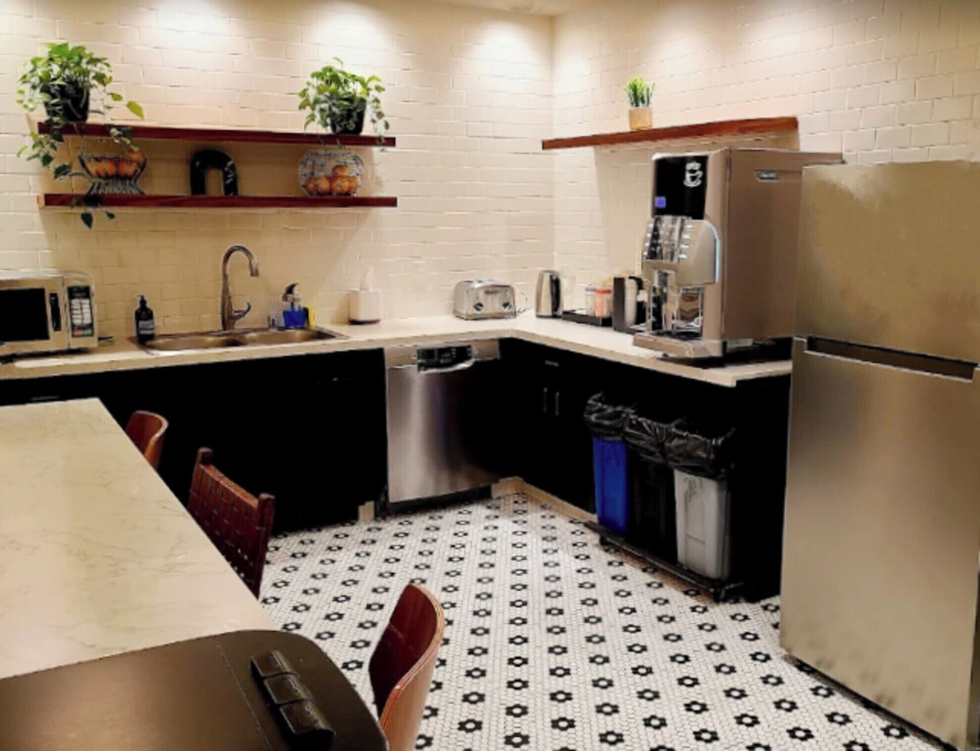 A compact kitchen with a microwave, toaster, and coffee maker. There are shelves with plants and a trash bin.