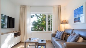 Un salon moderne avec un canapé, une table basse, un téléviseur et une fenêtre avec des rideaux.