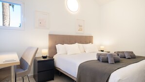 Une chambre d’hôtel moderne équipée d’un lit, de tables de chevet, d’un bureau et d’une chaise.