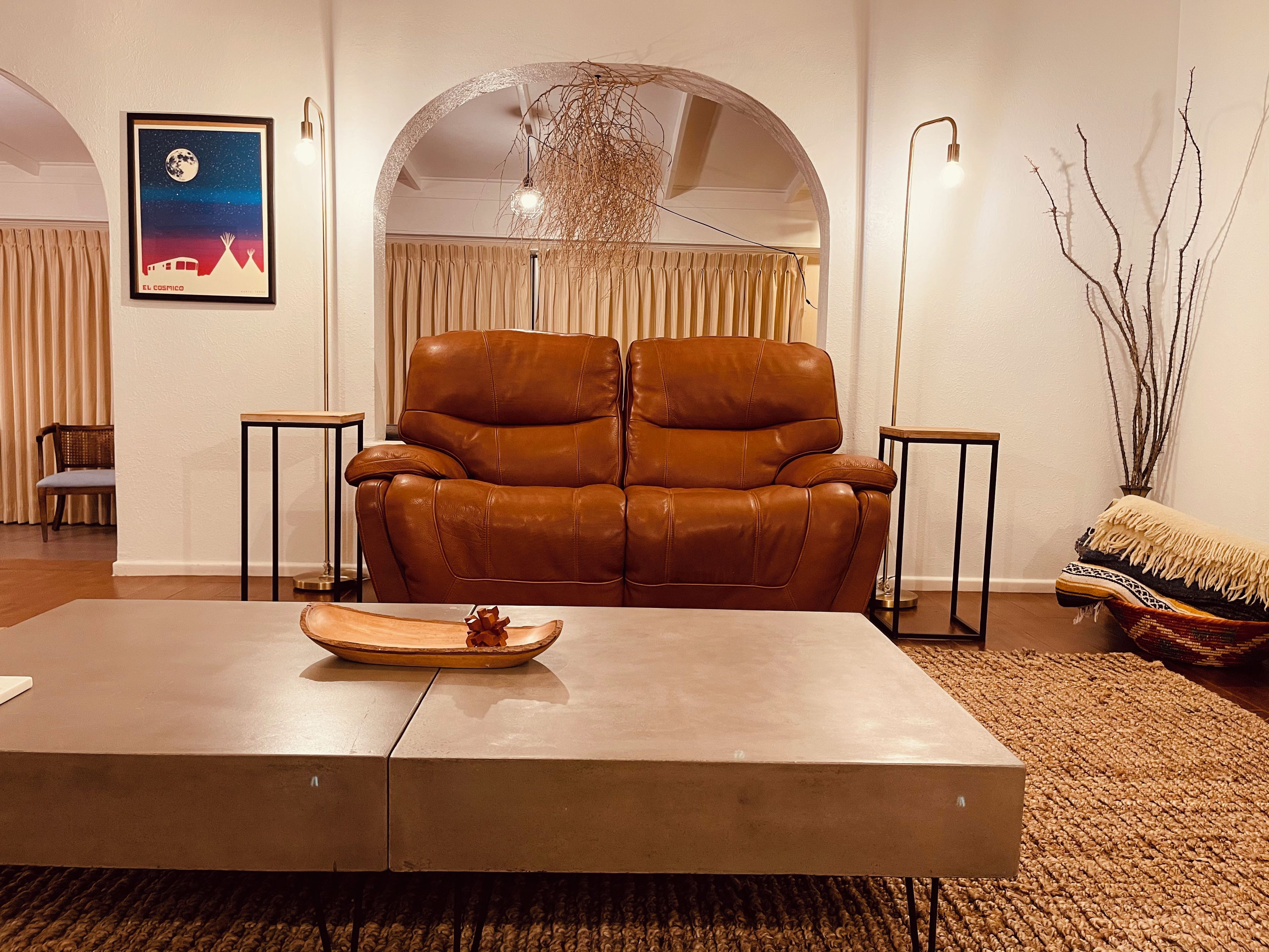 Een moderne woonkamer met een leren fauteuil, een houten salontafel en een kunstwerk in een lijst aan de muur.