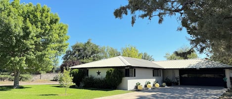 A residential house with a garage, a lawn, and a tree.