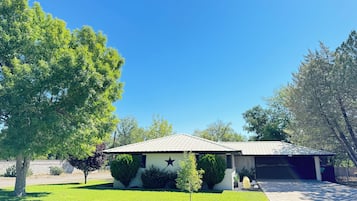 Ein Wohnhaus mit Garage, einem gepflegten Rasen und einem großen Baum.