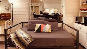 Quarto com cama, área de refeições e cozinha.