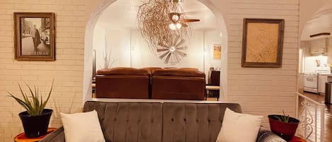 A living room with a sofa, a decorative ceiling light, and a brick wall.