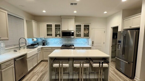 Una cocina moderna con una isla central, electrodomésticos integrados y un salpicadero de azulejos en espiga.