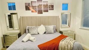 Un dormitorio ordenado con cama, dos mesitas de noche y una ventana con persianas.