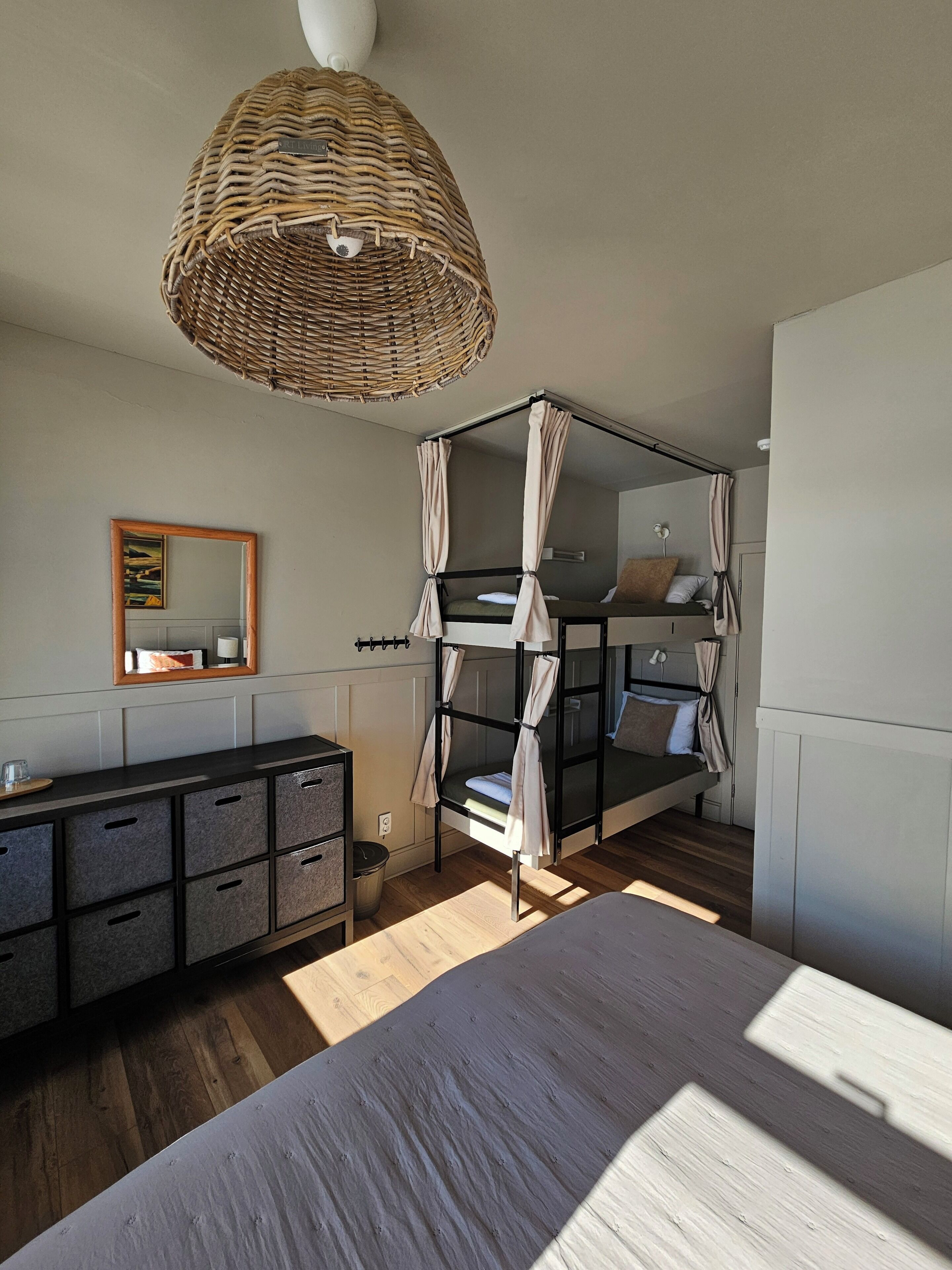 A bedroom with a bunk bed, a dresser, a mirror, and a hanging light fixture.